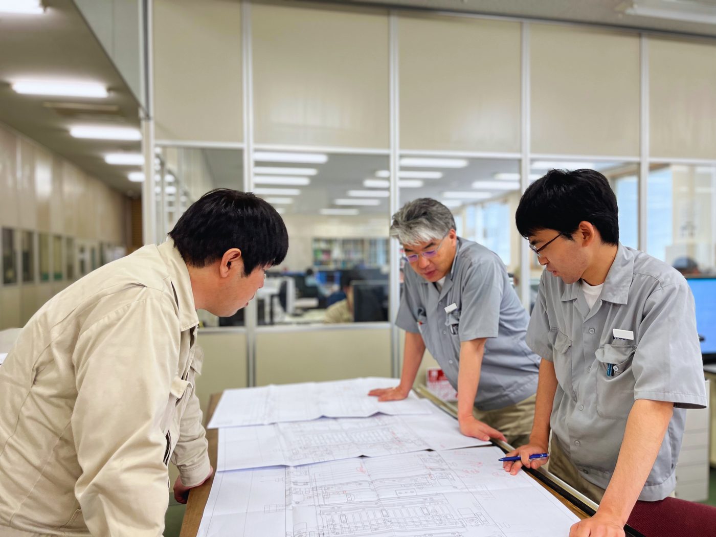 図面を囲んで意見を交わす社員